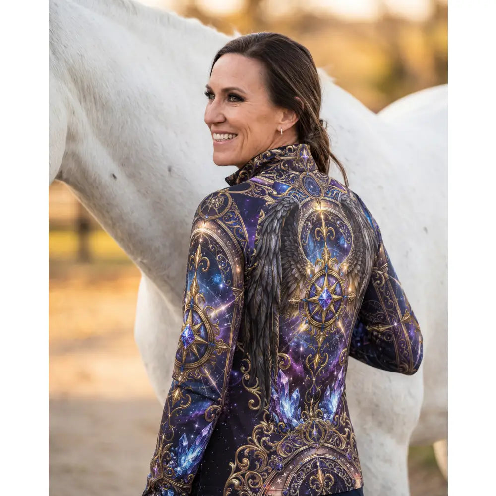 A woman wears an astral ascension performance equestrian sun shirt with cosmic winged horse print in deep blues and gold