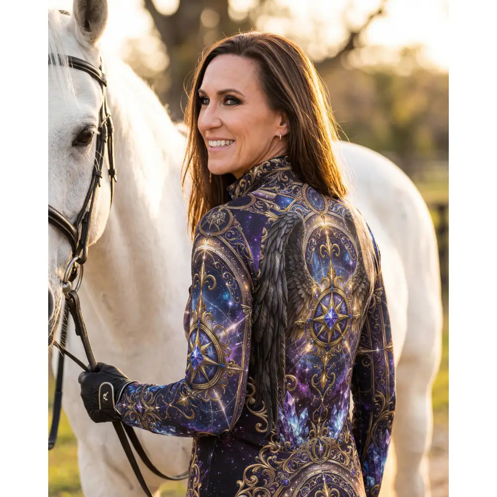 A woman wears an astral ascension performance equestrian sun shirt with cosmic purple patterns and gold accents