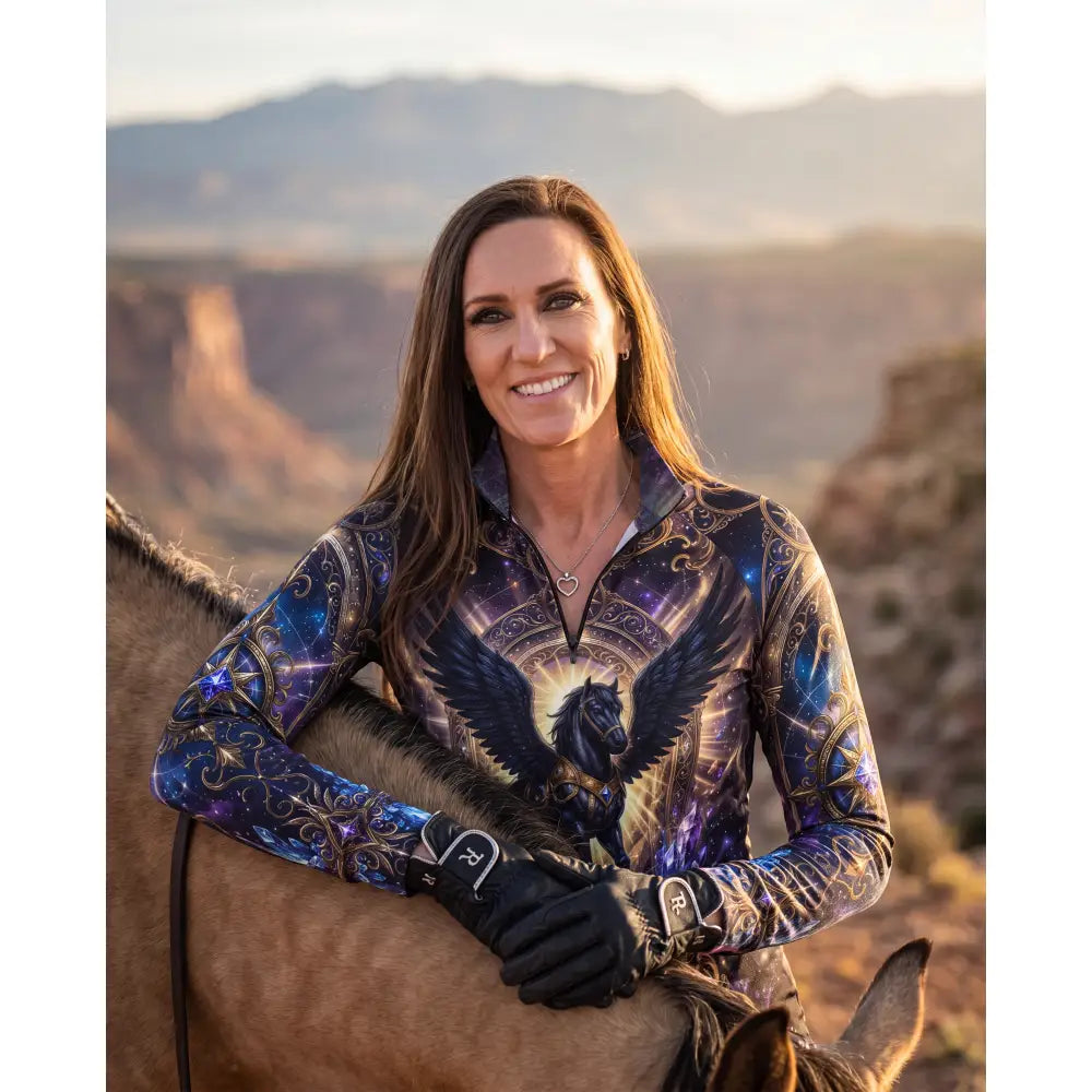A woman wearing an astral ascension performance equestrian sun shirt with a cosmic winged horse design