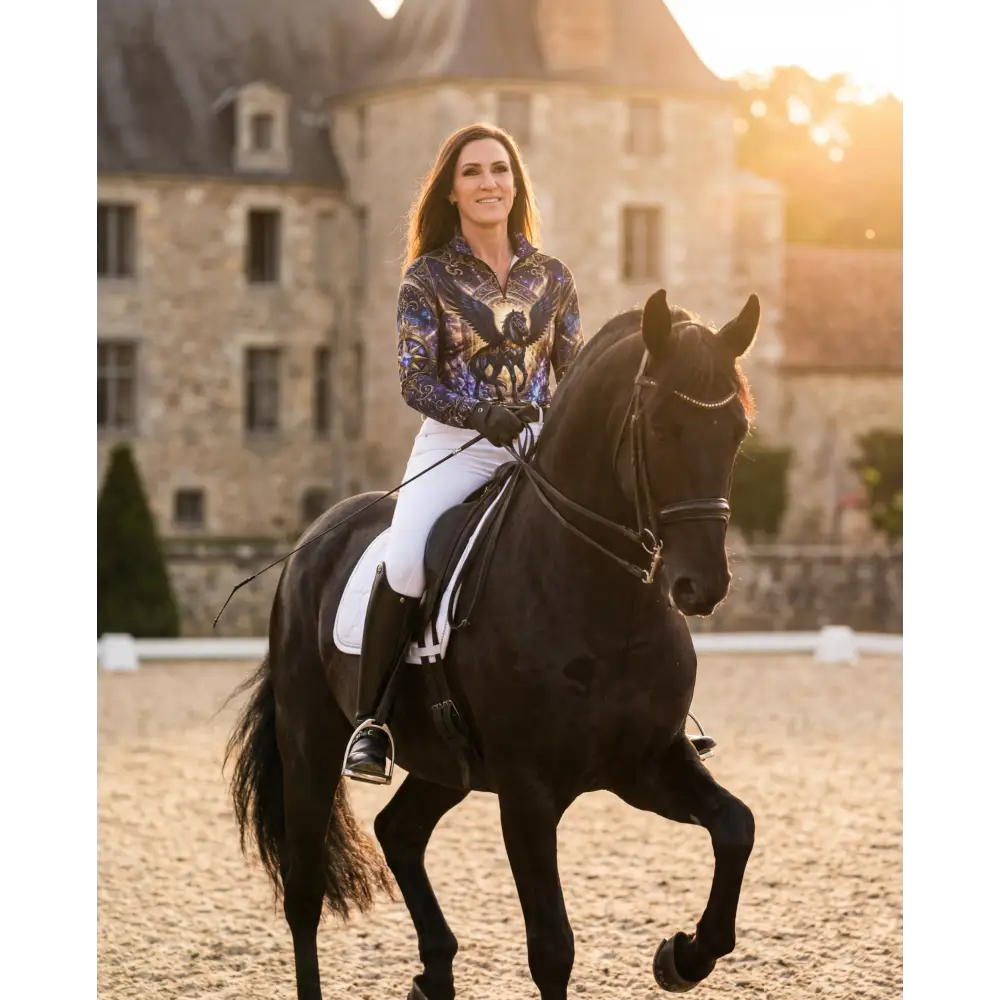 A woman rides a sleek black horse wearing an astral ascension performance equestrian sun shirt with upf50 plus protection