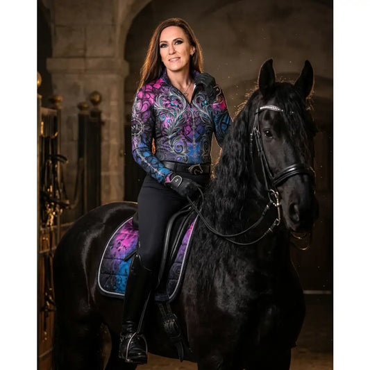 A woman wears a midnight radiance lightweight performance equestrian sun shirt with purple floral patterns on a black horse