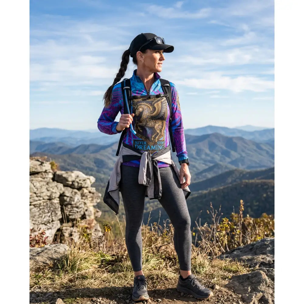 Woman wearing a vibrant purple and blue never stop dreaming performance equestrian sun shirt with eagle graphic and dark leggings
