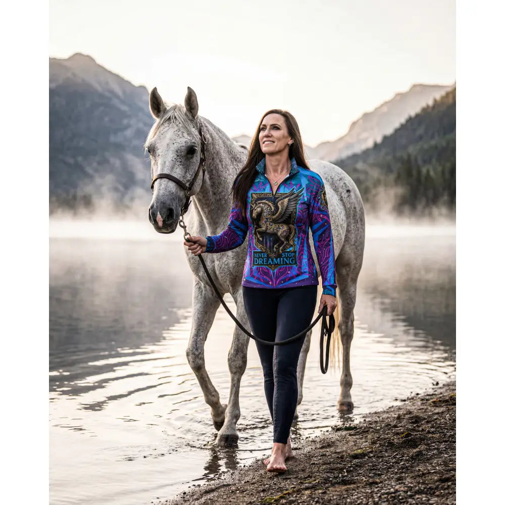 Vibrant blue and purple equestrian sun shirt with golden griffin graphic and never stop dreaming text performance equestrian sun
