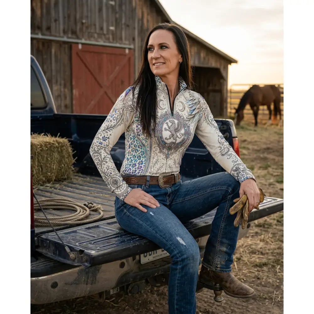 A woman wearing a cream western-style panthera arcana equestrian sun shirt with gray teal embroidery by karen reinertson