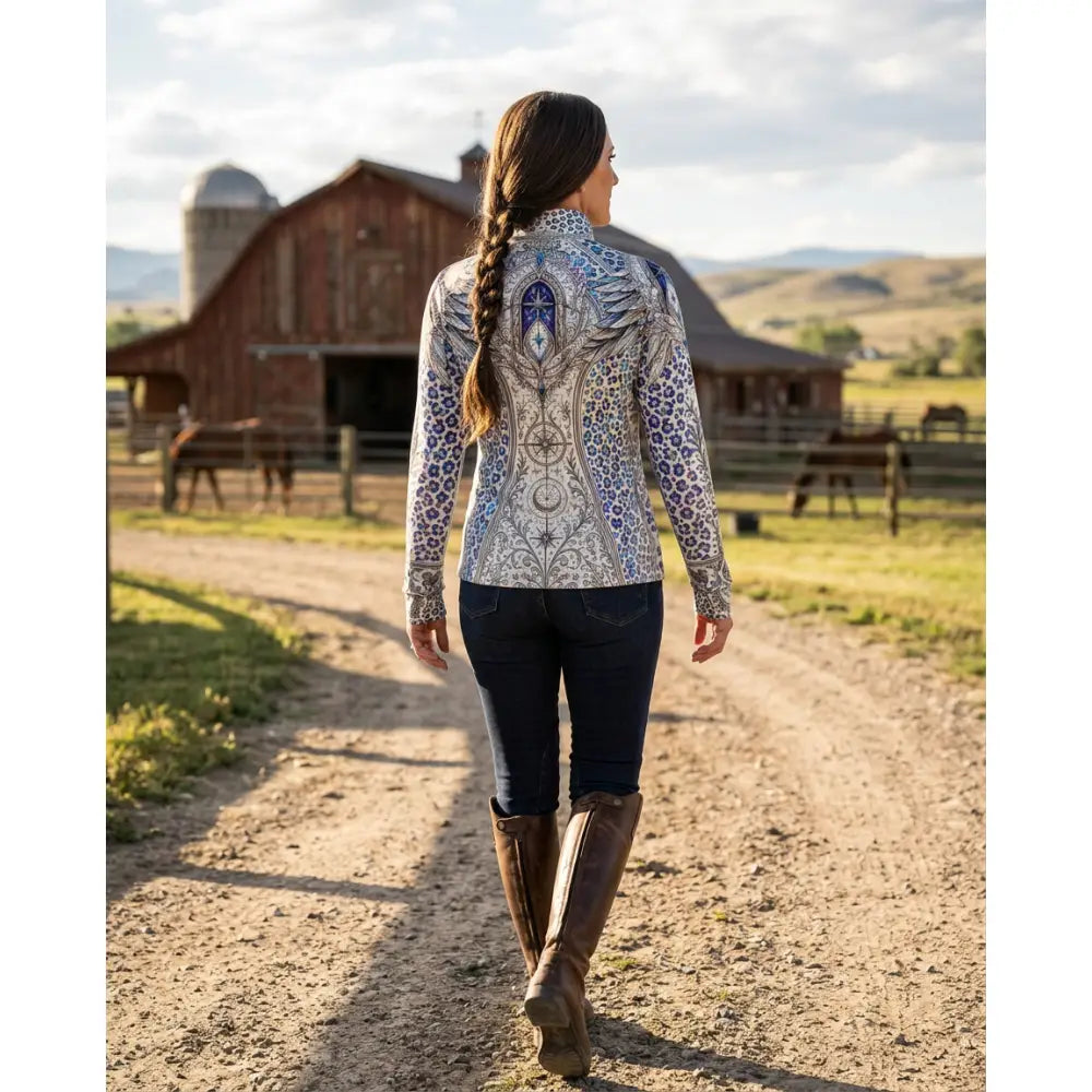 A woman walks away showing the back of the panthera arcana equestrian sun shirt with blue white arcane wing print