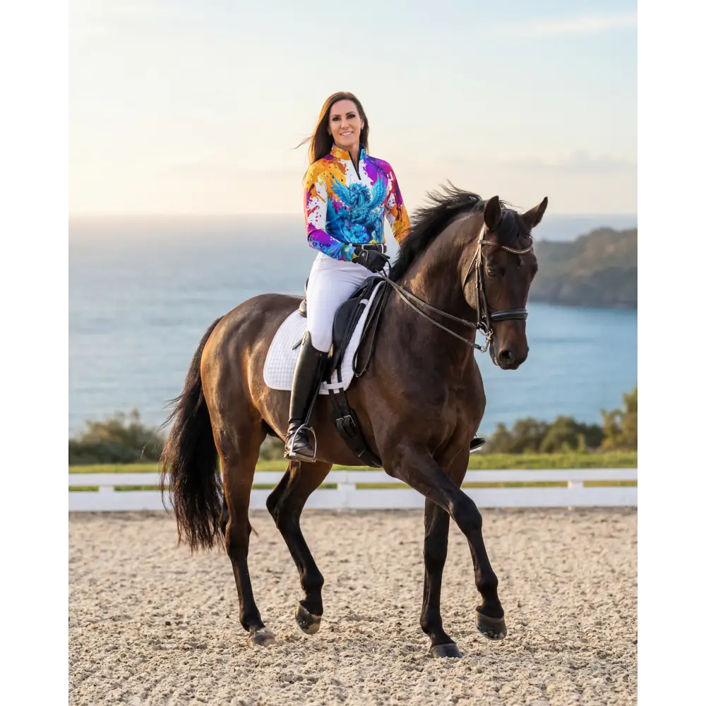 A woman rides a dark brown horse wearing a vibrant multicolored riptide radiance performance equestrian sun shirt upf50+