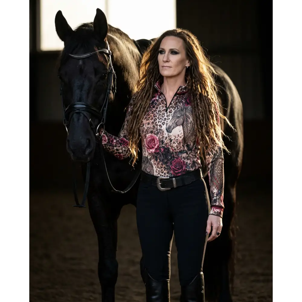 A woman wearing a long-sleeved leopard-print rosae equiferus UPF50 equestrian sun shirt with floral and horse motifs