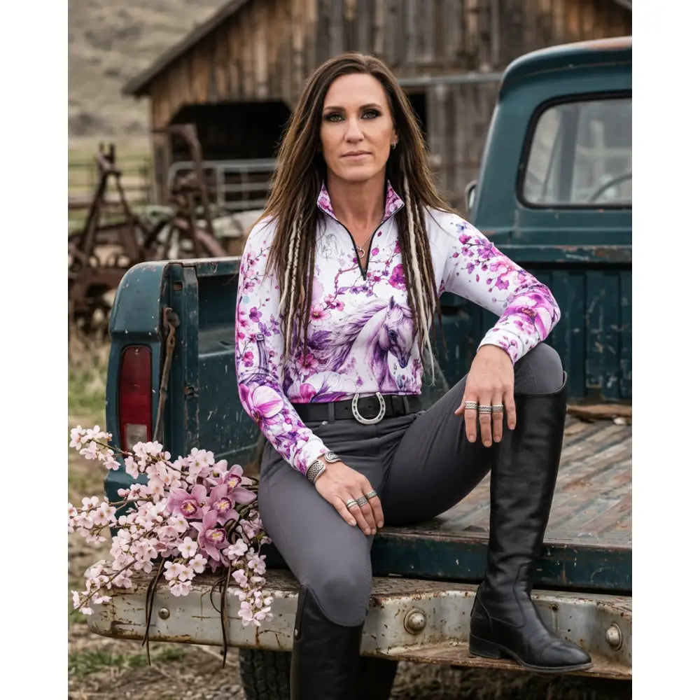 A woman wearing a sakura wildheart equestrian sun shirt with orchid cherry blossom horse print by karen reinertson