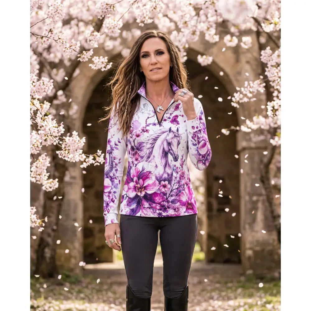 A woman wears a sakura wildheart orchid and cherry blossom horse print upf50+ equestrian sun shirt by karen reinertson