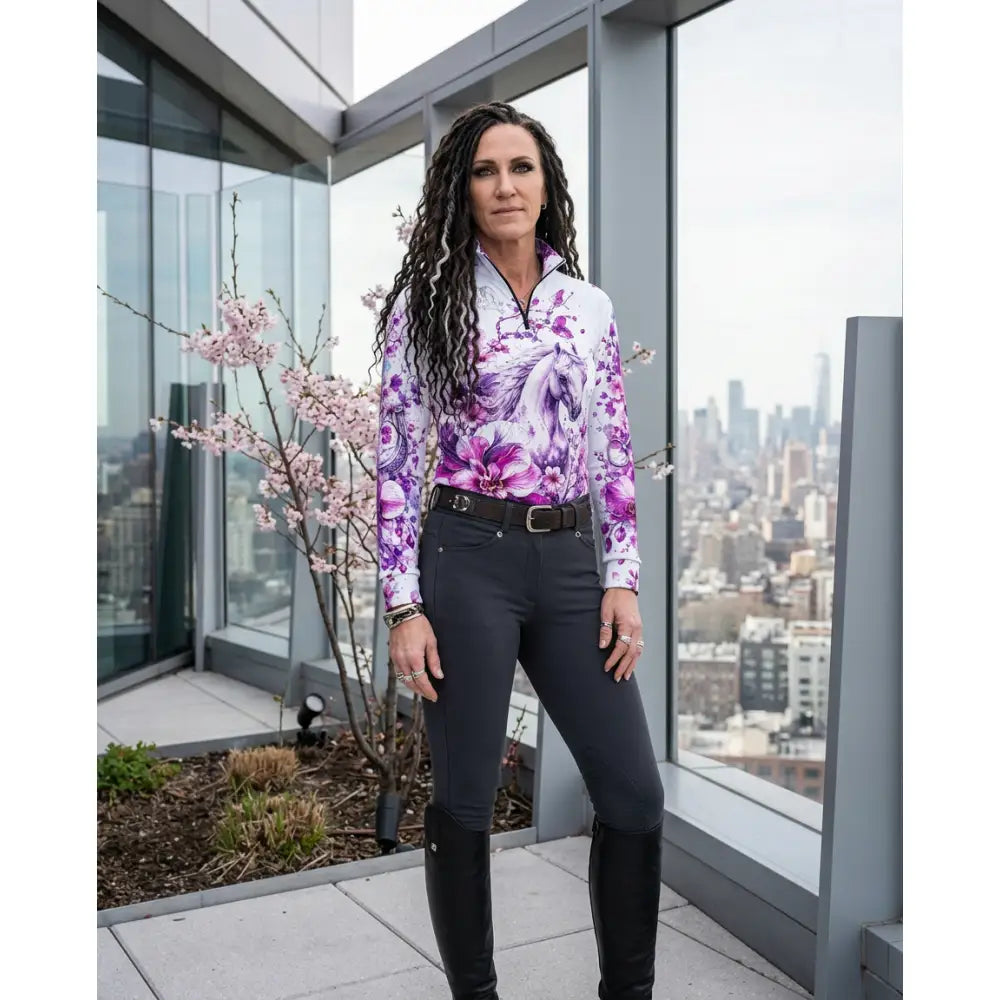 A woman wears the sakura wildheart long-sleeved white and purple floral UPF50+ equestrian sun shirt by karen reinertson