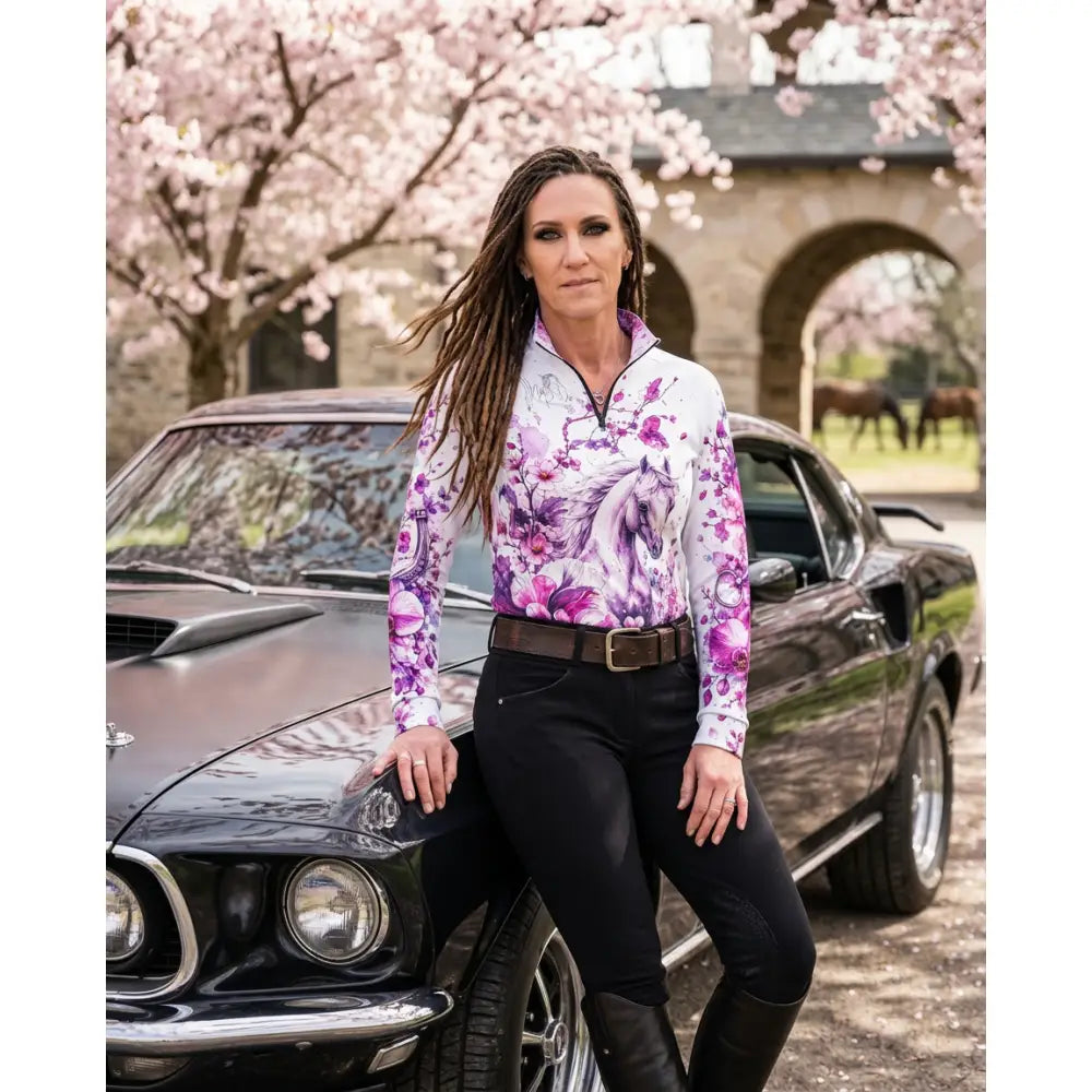 A woman wearing a sakura wildheart karen reinertson orchid cherry blossom horse print upf50+ equestrian sun shirt
