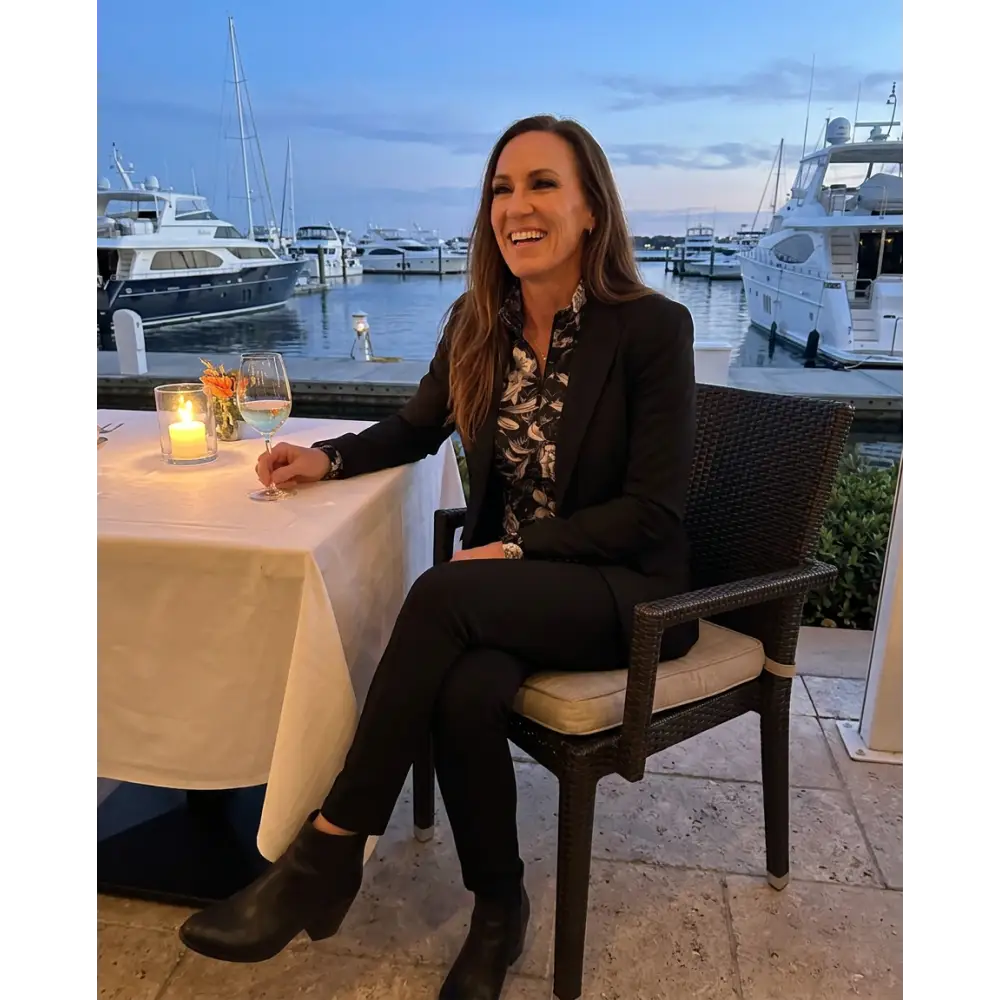 Woman wearing a black shadow bloom performance equestrian sun shirt upf50+ seated at an outdoor dining table