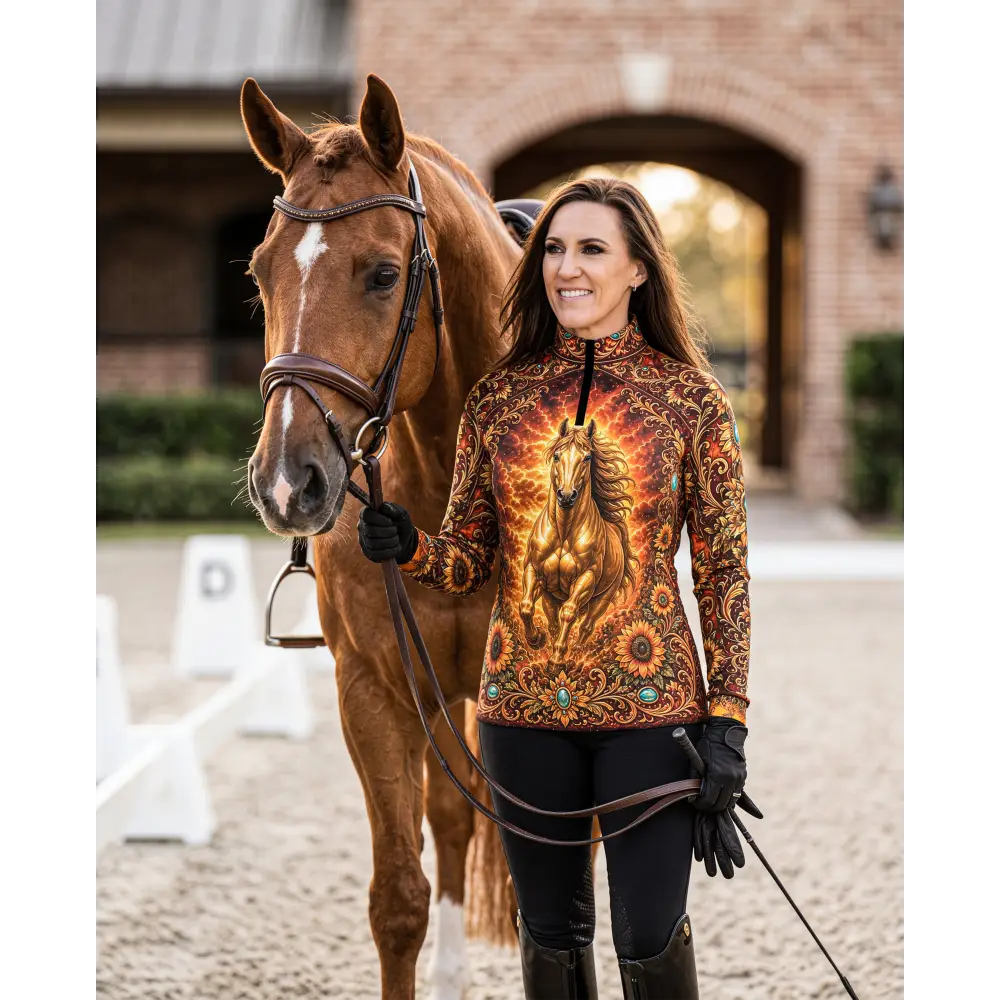 A woman wears a long-sleeved sunfire sovereign performance equestrian sun shirt with a golden horse and turquoise accents