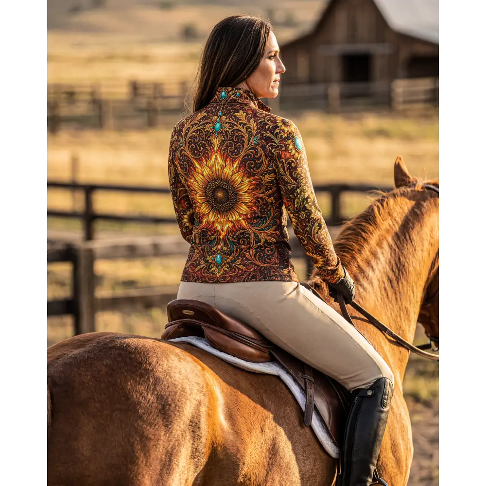 A woman wears a long-sleeved sunfire sovereign riding jacket with gold sunflower design and turquoise stone accents