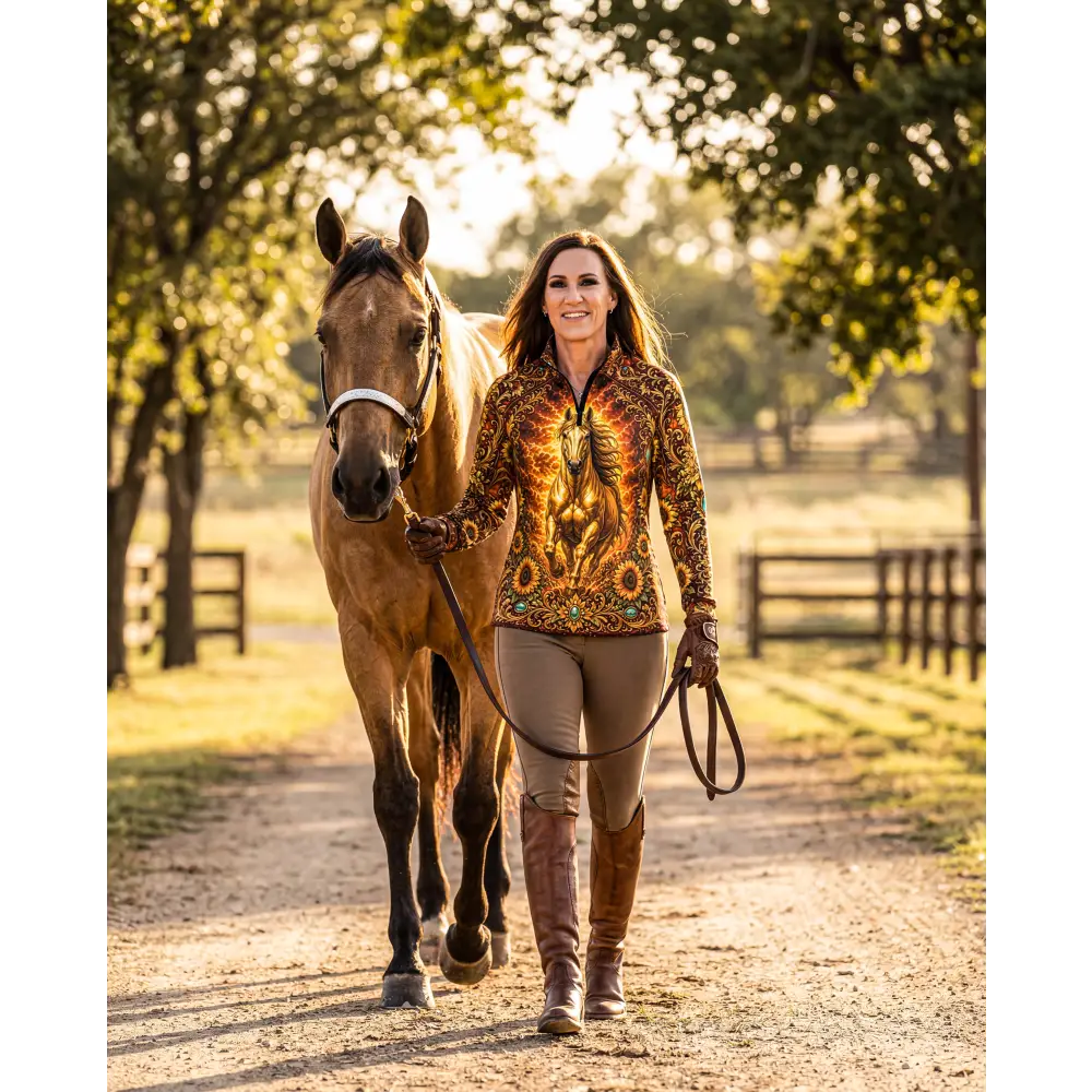 A woman wearing a vibrant long-sleeved sunfire sovereign equestrian sun shirt with golden horse and brown patterns
