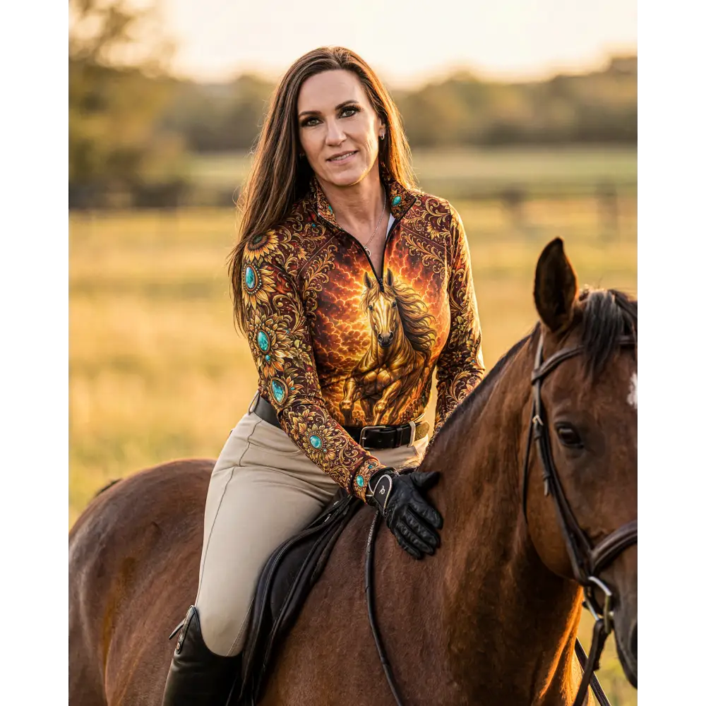 A woman wears a long-sleeved sunfire sovereign performance equestrian sun shirt with flame pattern and turquoise accents