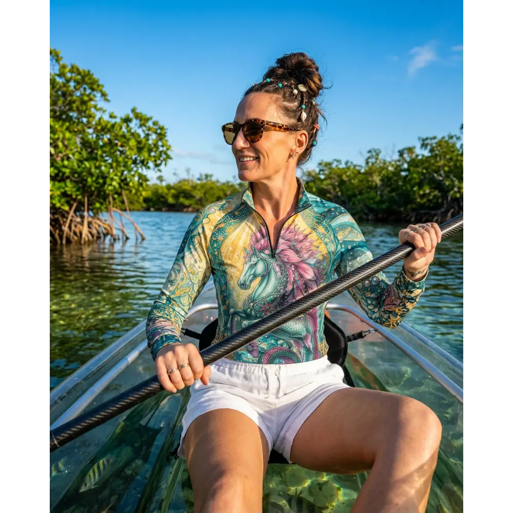 A woman wearing a tidewoven reefborn performance equestrian sun shirt upf50 plus with a vibrant unicorn and floral design