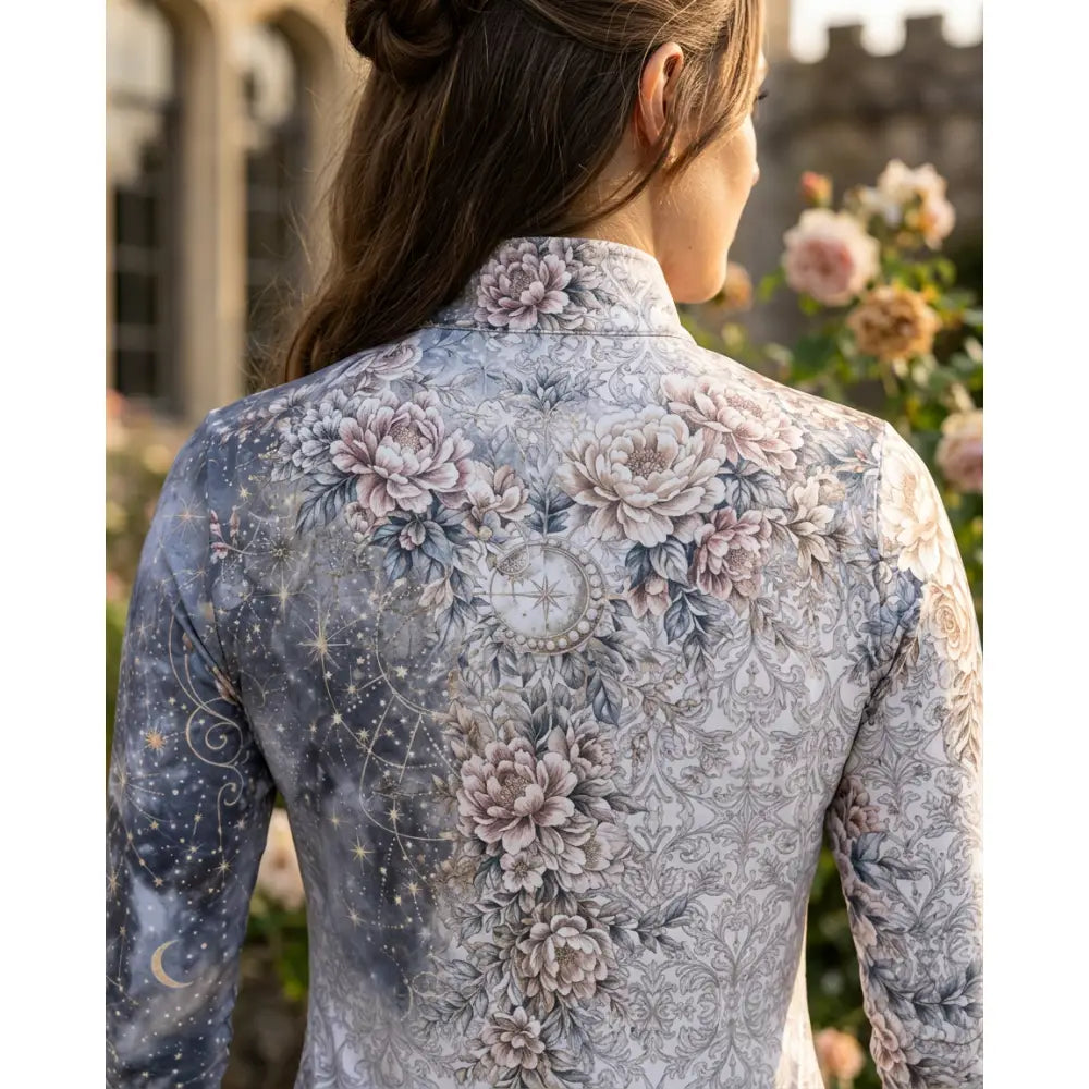 A woman wears a soft gray and muted pink karen reinertson unicornis caelestis equestrian sun shirt with celestial floral print
