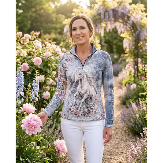 A woman wears the unicornis caelestis equestrian sun shirt by karen reinertson with a celestial unicorn print on blue-gray fabric