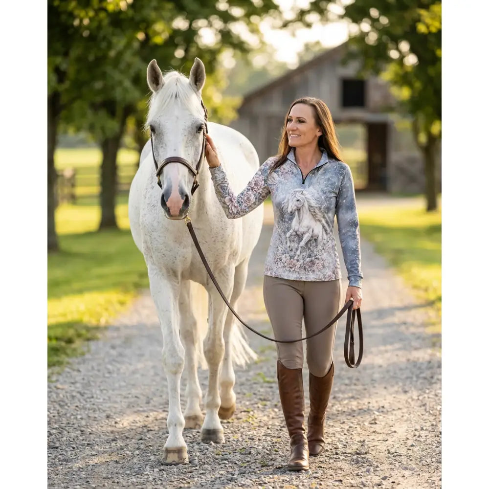 Woman wearing a gray and blue patterned unicornis caelestis equestrian sun shirt with a white horse graphic by karen reinertson