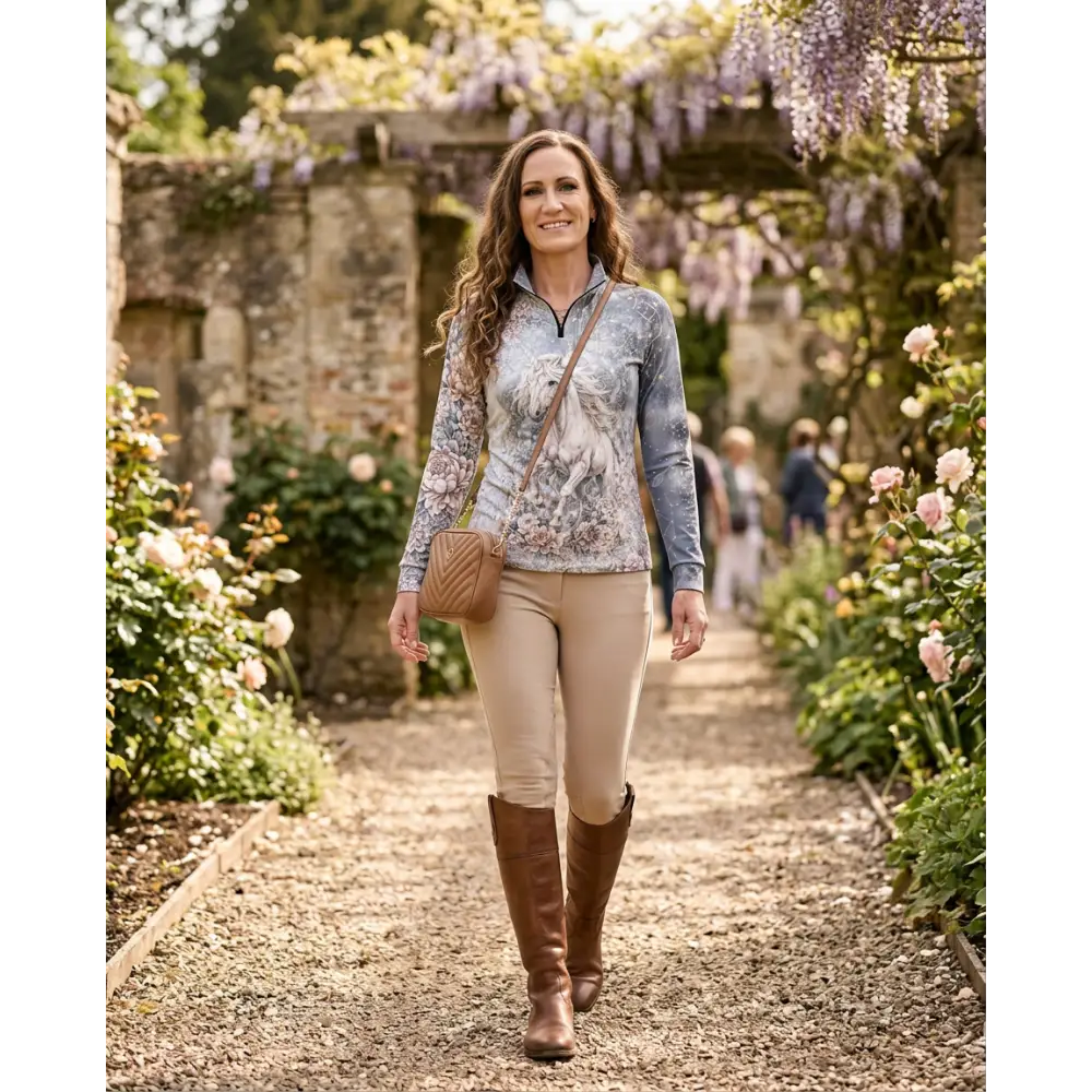 A woman wearing a long-sleeved unicornis caelestis performance equestrian sun shirt upf50 with white horse floral pattern