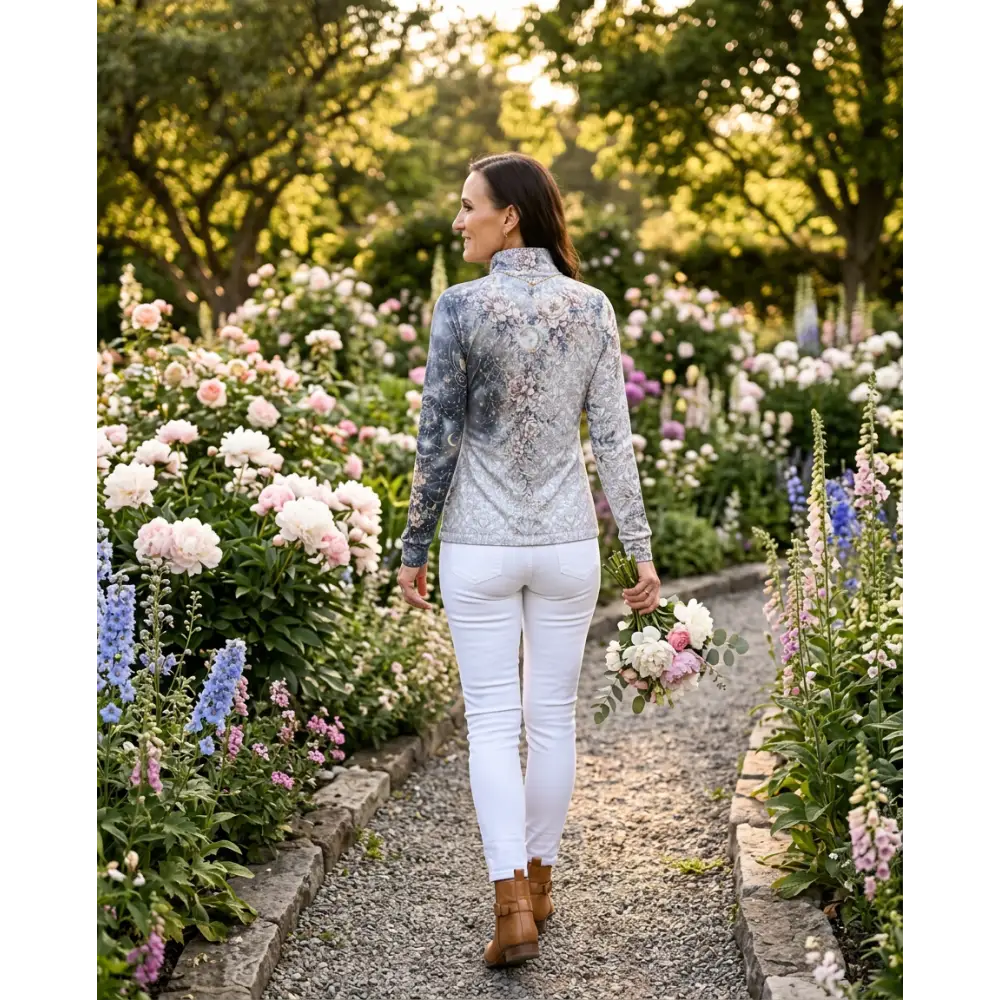 A woman wearing a unicornis caelestis performance equestrian sun shirt upf50 plus with gray and pink floral pattern
