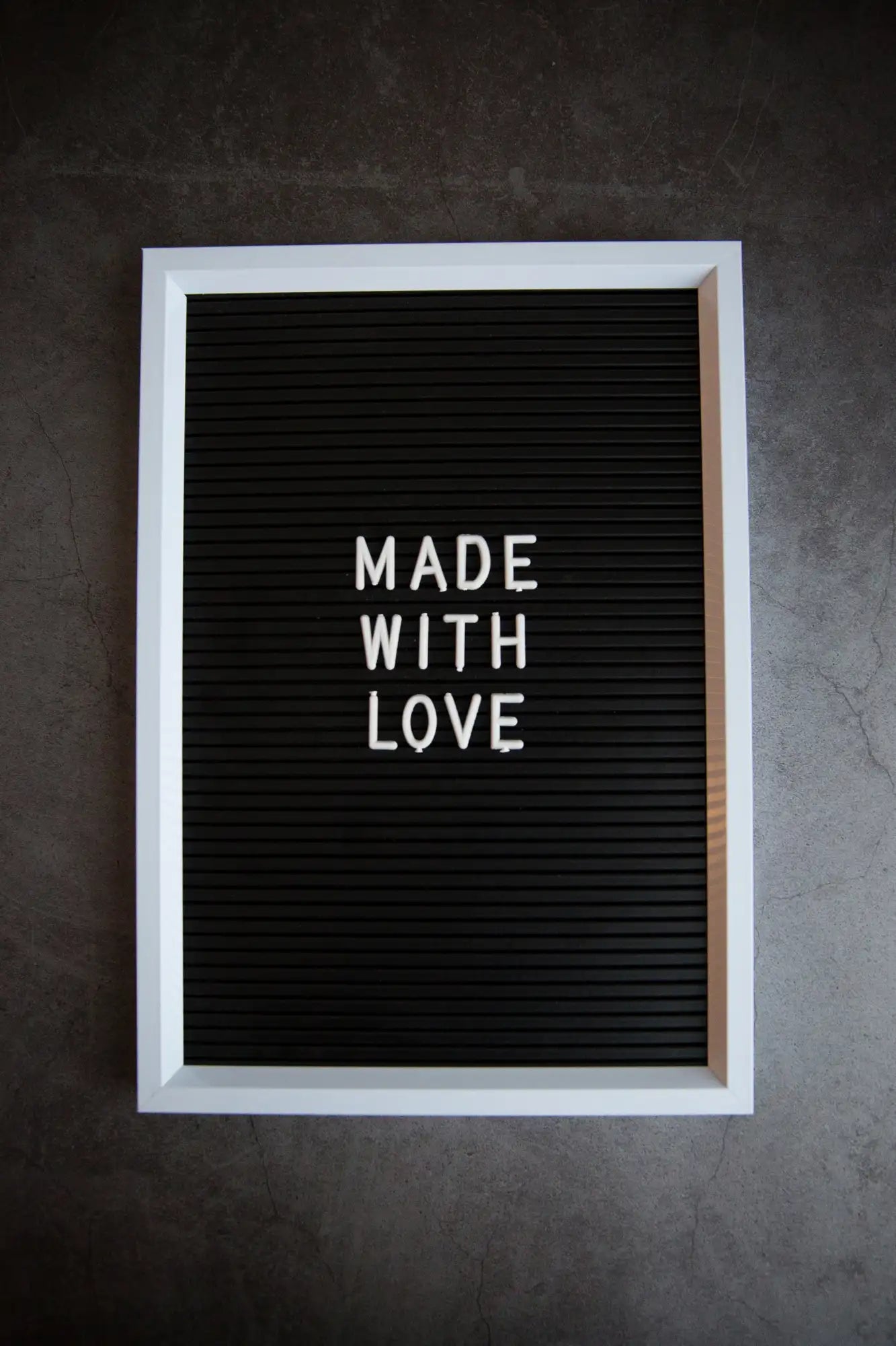 White-framed black letterboard displaying ’made with love’ in white letters.