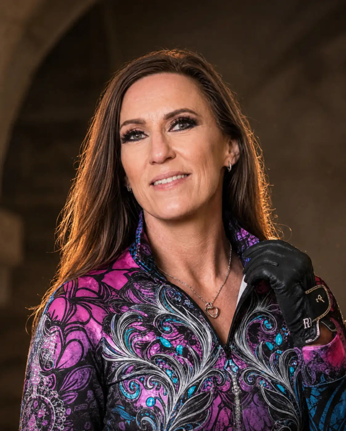 A woman wearing a vibrant purple and teal patterned zip-up jacket with intricate floral designs.
